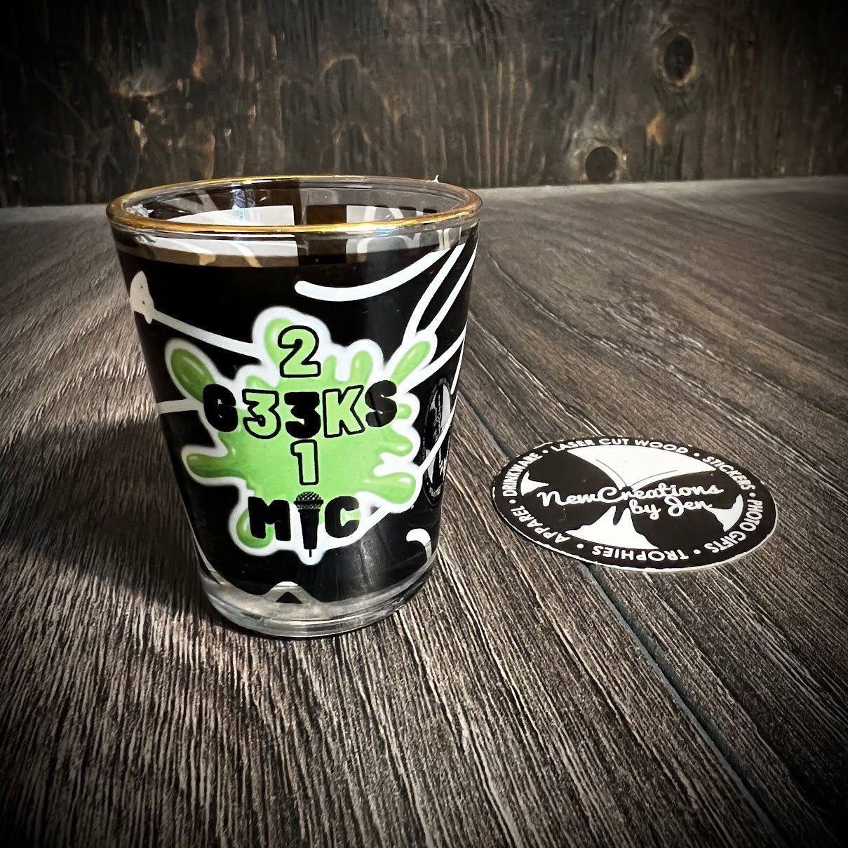 shot glass with 2 G33KS 1 MIC artwork on a green splat