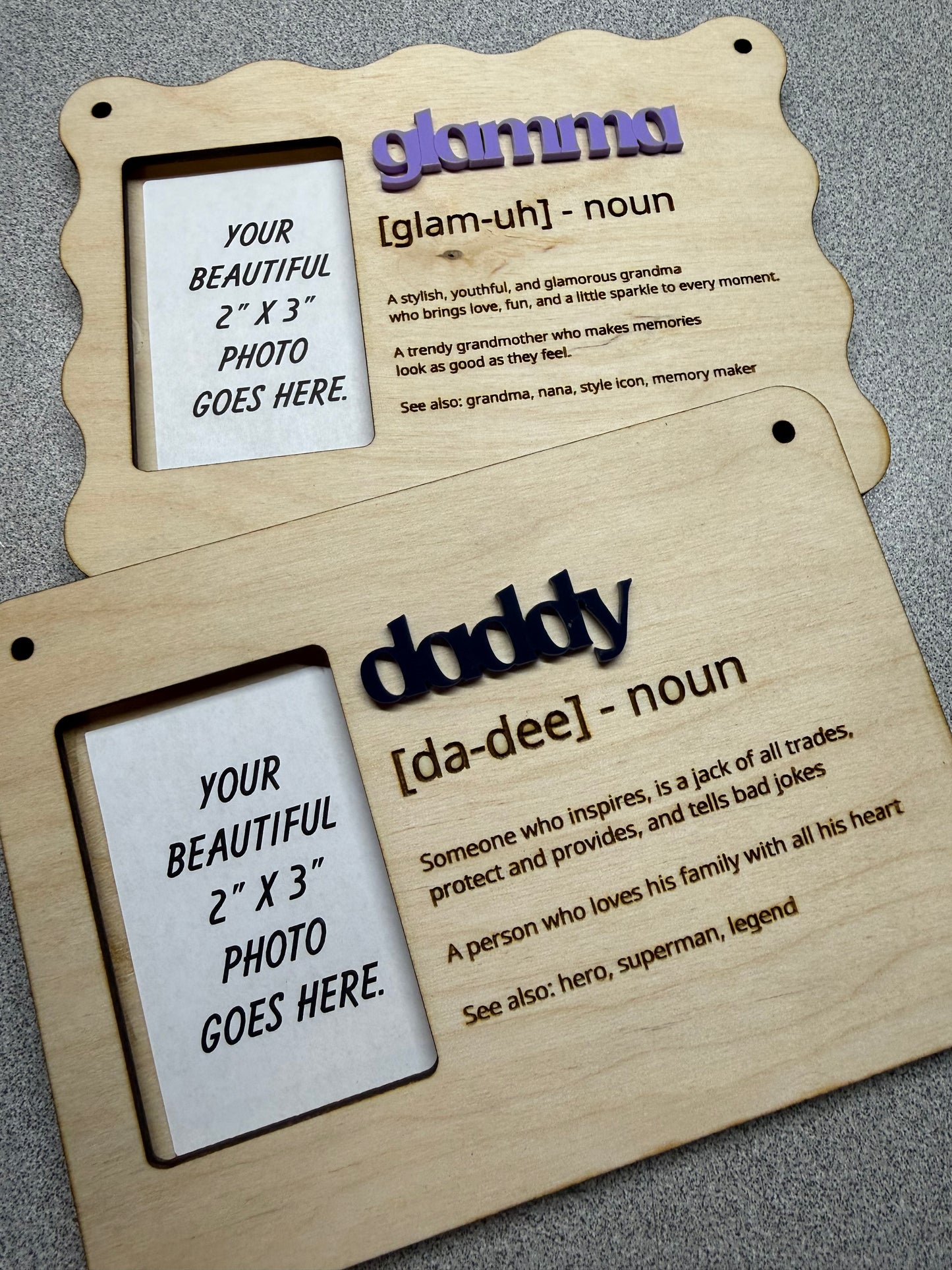 Two wooden hanging photo frames with family nicknames & definitions text on a dark surface