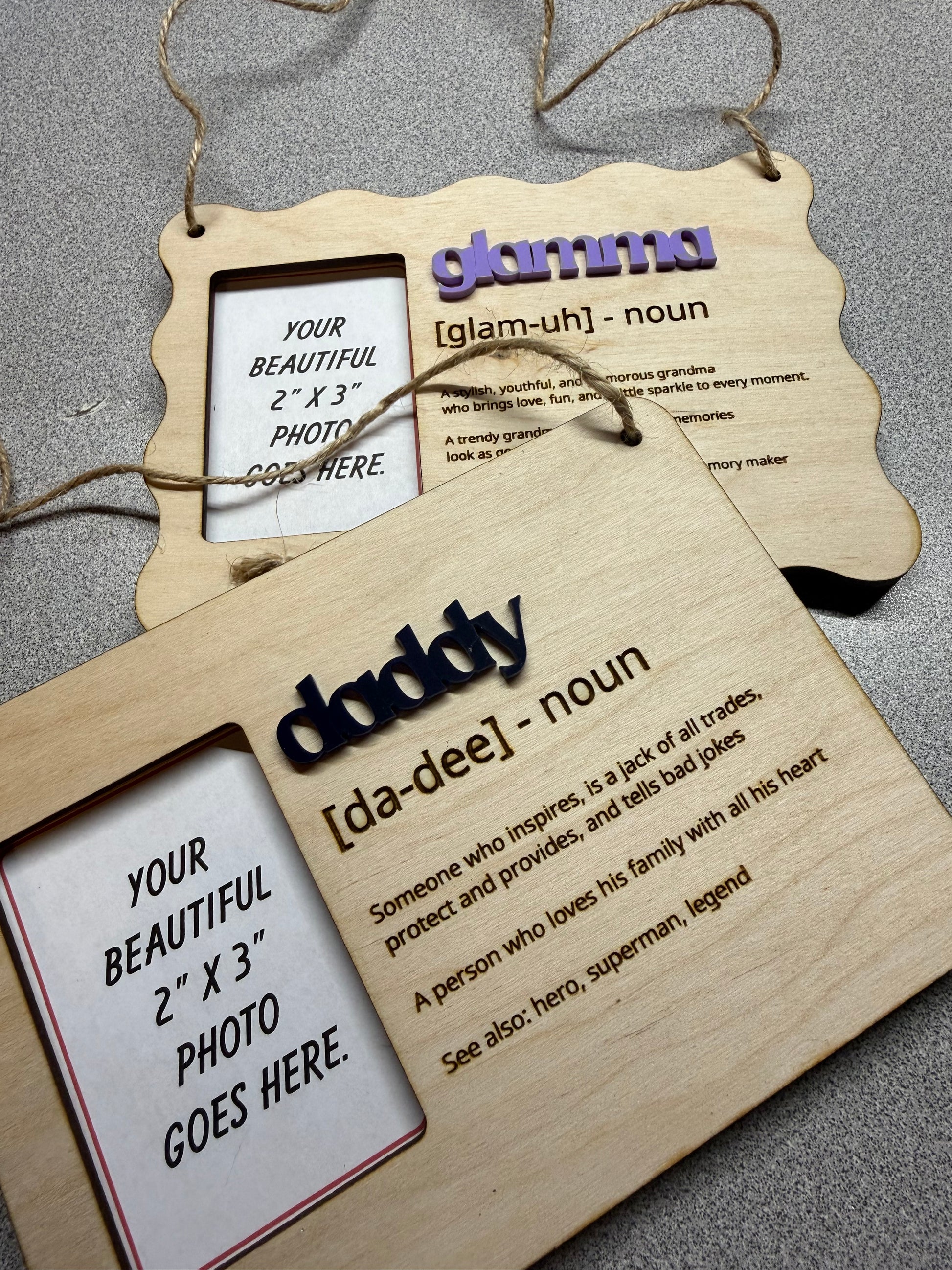 Two wooden hanging photo frames with family nicknames & definitions text on a dark surface