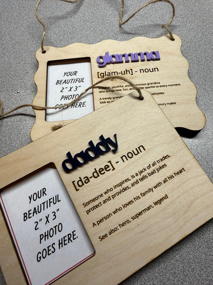 Two wooden hanging photo frames with family nicknames & definitions text on a dark surface