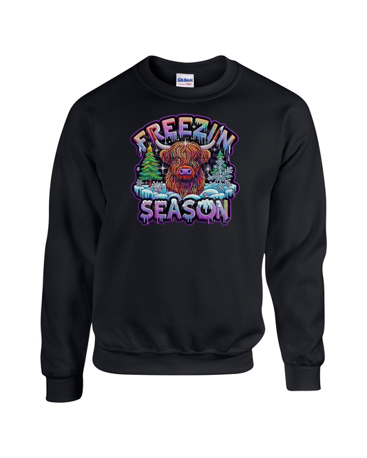 Black sweatshirt with a colorful graphic of a Highland cow and 'Freezin' Season' text on a white background.